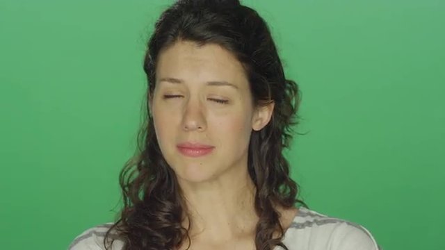 Young woman beginning to cry, on a green screen studio background