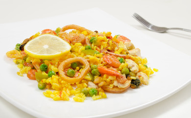 Paella with chicken and seafood on a white plate, close-up, side view
