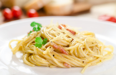 Pasta Carbonara with bacon on a white plate, close-up, side view
