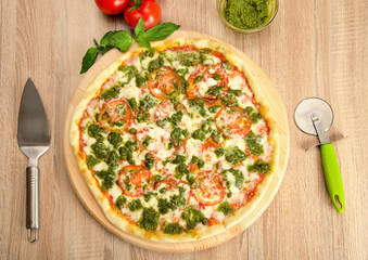 Pesto Pizza with cheese, tomatoes and capers on a wooden board, top view
