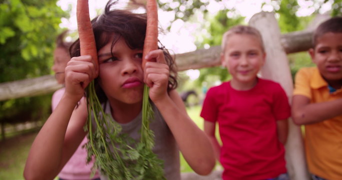 Little boy being silly with two carrots and his friends