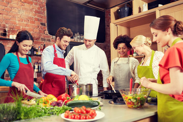 happy friends and chef cook cooking in kitchen