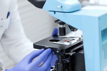 close up of hands with microscope and blood sample