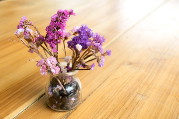 Purple flowers in a glass vase on wood table