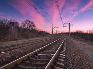 Fototapeta na wymiar Railroad at colorful sunset on the background of beautiful blue sky. Railway landscape