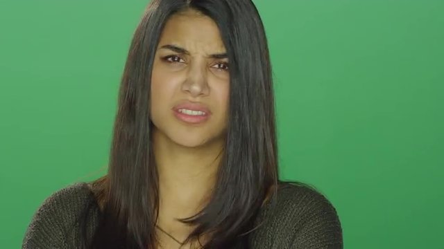 Young woman looking angry, on a green screen studio background