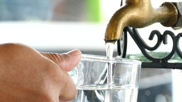 Filling glass of water from old brass faucet.