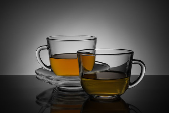 Two glass cup with tea and saucer on a black and white backgroun