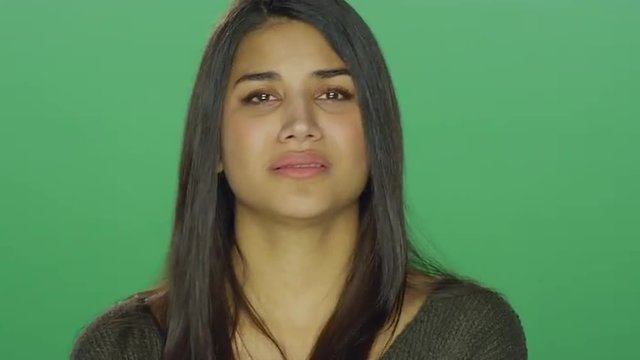 Young woman starting to recover after crying, on a green screen studio background