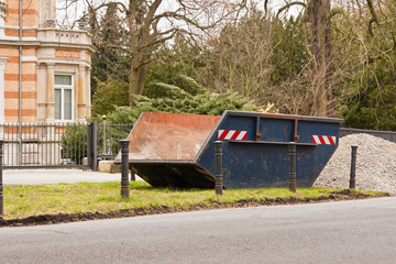 Ein leerer blauer Container steht auf dem Rasen an einer Strasse
