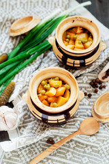 
National Russian , Ukrainian and Belarusian cuisine , baked potatoes with meat in the pot , onion , pepper, garlic , pickled cucumber and spices on a wooden background