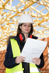 female engineer looking at blueprints in construction site