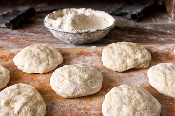 Fototapeta na wymiar Raw bread Rising on Table with Bowl of Flour
