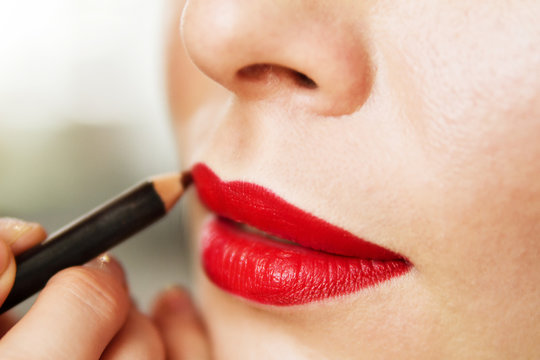 Lip makeup, red lipstick, a beautiful young brunette woman doing makeup