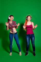 Two young women having fun, listening to music with headphones