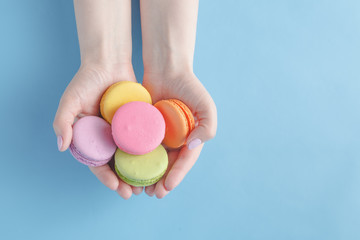 Girl holding colorful French macarons in hands