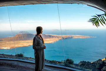 Woman looking on Graciosa island from El Rio viewpoint on Lanzarote island in Spain