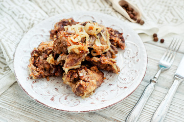 
Fried chicken liver with onions and spices on a wooden background