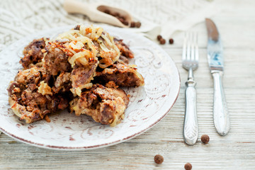 
Fried chicken liver with onions and spices on a wooden background