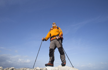 A traveler stands on top of a mountain and looks out to sea.