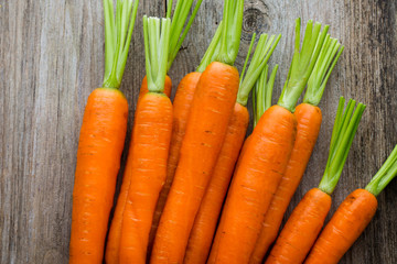Fresh carrots bunch on rustic wooden background.