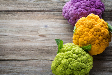 Rainbow of eco cauliflower on the wooden table.