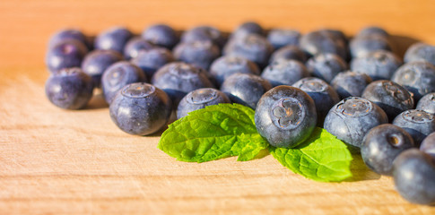 Soft focused blueberries with leaves of mint on wood