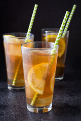 Ice tea with lemon. Black stone background
