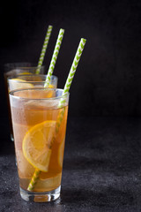 Ice tea with lemon. Black stone background
