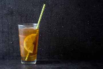 Ice tea with lemon. Black stone background
