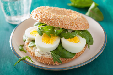 breakfast sandwich on bagel with egg cream cheese arugula