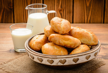 Traditional  russian pastry piroshki and milk on wooden table.