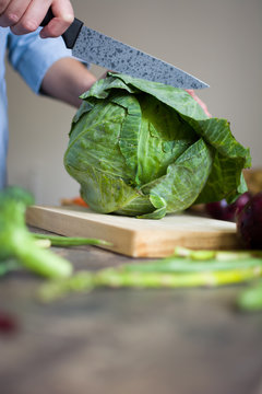 Close up of man's hand cutting cabbage on wooden board