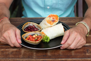 Burrito on ceramic ware, the Man eats a burrito, tasty, it is useful, vegetarian food