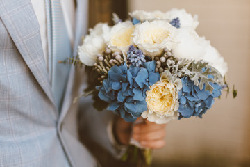 groom hold wedding bouquet in his hand
