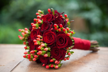 Wedding bouquet of red roses and hypericum, tied with a red ribbon