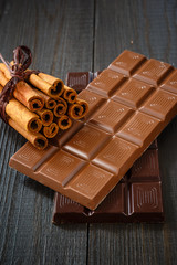 Different chocolate with cinnamon on dark wooden boards