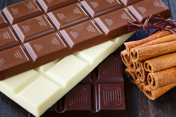 Assorted chocolate with cinnamon on dark wooden boards close-up