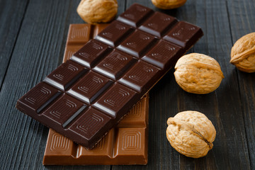 Different chocolate with walnuts on dark wooden boards