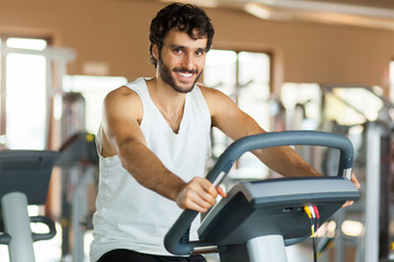 Fototapeta na wymiar Man in the gym, exercising his legs doing cardio training on bicycle