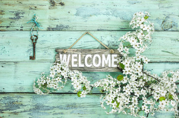 Welcome sign hanging by skeleton key and spring flowers 