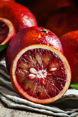 Cut Sicilian bloody oranges on a gray cloth and a knife on an ol