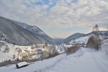 Wintry rural mountain scenery in the valleys of Bucegi mountains in Magura village, Brasov county, Romania. Touristic destinations for winter vacation.