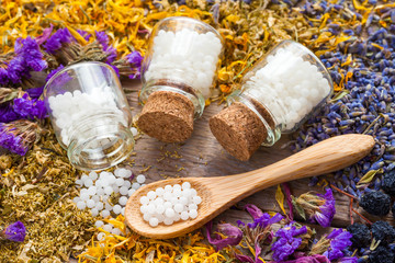 Bottles of homeopathy globules and dry healthy herbs. Selective