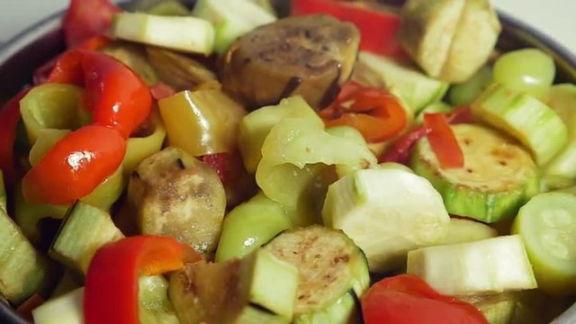 Slow motion close-up shot of a cooking delicious vegetarian dish. Female hand stirring vegetables with plastic spoon in stewpan