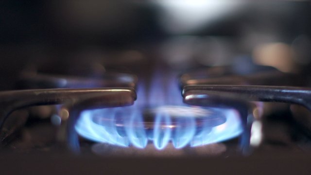 Stove top burner igniting into a blue cooking flame in 4K UHD. 