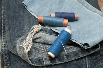 Old torn jeans on a background of burlap.  - obrazy, fototapety, plakaty