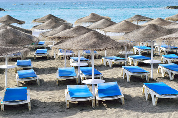 Fototapeta na wymiar Umbrellas and chairs outdoors on Fanabe beach in Tenerife island