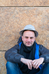 Fototapeta premium Man sitting against granite wall