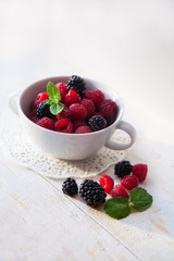 Juicy fresh blueberries, raspberries and blackberries in a white plate